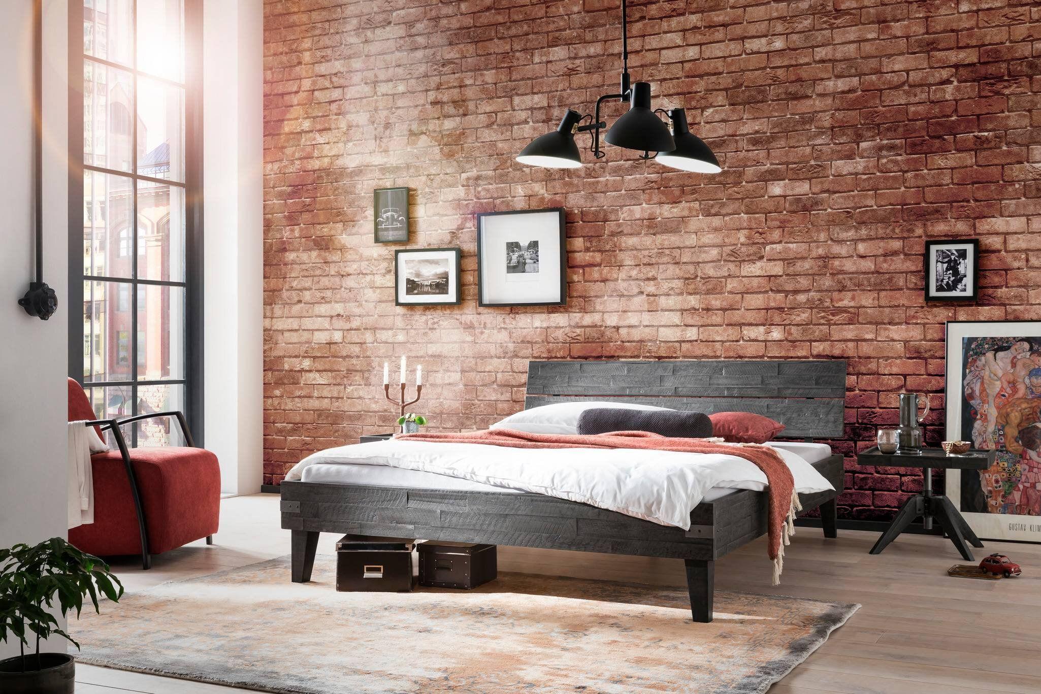 Schlafzimmer im Industrial-Stil mit Backsteinwand, dunklem Holzbett und moderner Beleuchtung.