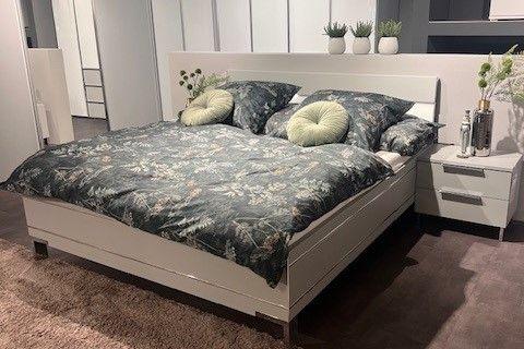 Weißes modernes Bett mit passenden Nachttischen, dekoriert mit floraler Bettwäsche und eleganten Details.