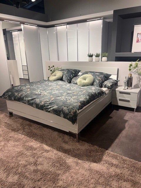 Weißes modernes Bett mit passenden Nachttischen, dekoriert mit floraler Bettwäsche und eleganten Details.