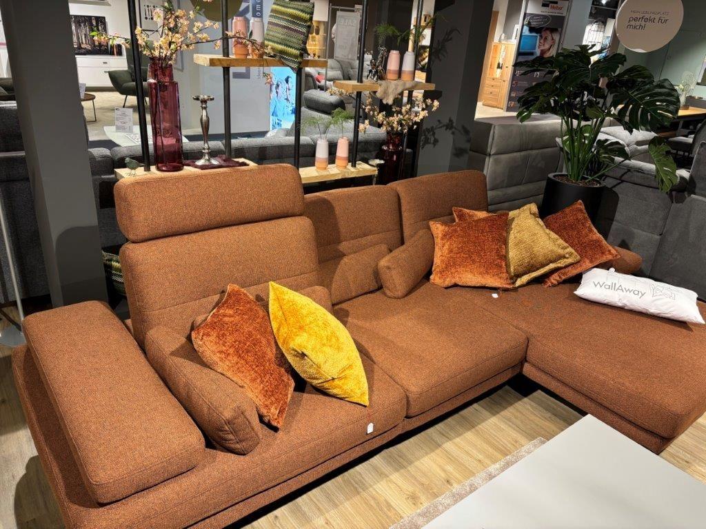 Rostrote Couchgarnitur mit modernen gemusterten Kissen, kombiniert mit einem Holztisch und runden Beistelltischen auf einem dunklen Teppich.