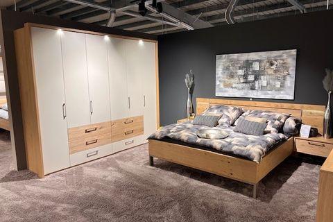 Modernes Schlafzimmer mit Holz- und Weißelementen, bestehend aus Kleiderschrank, Doppelbett und Nachttischen, auf einem weichen Teppichboden.