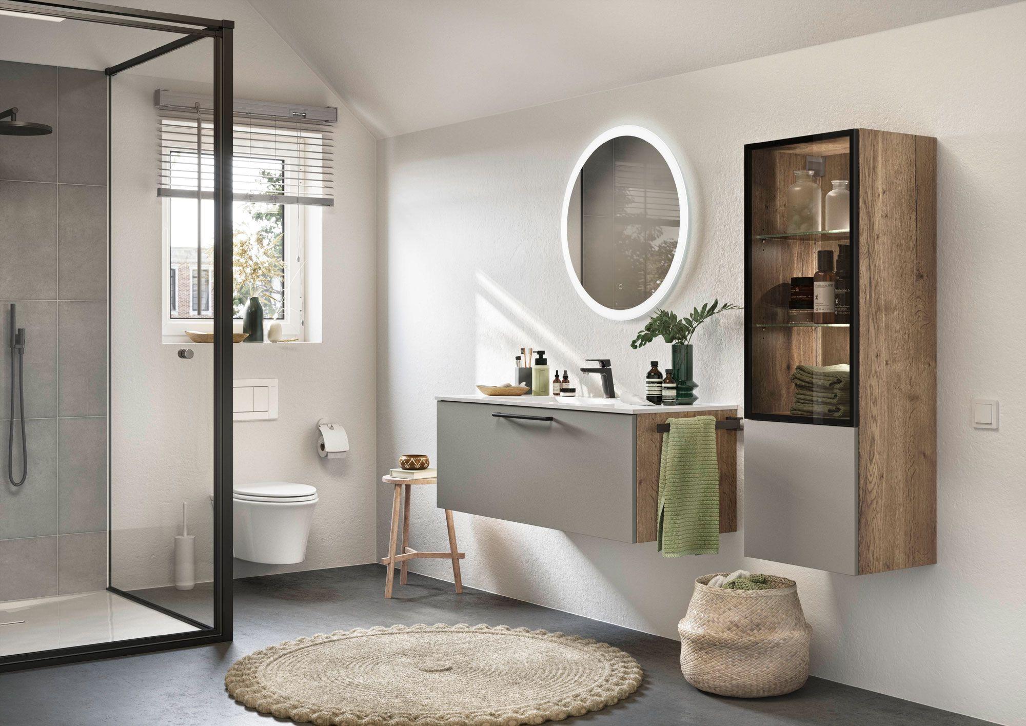Modernes Badezimmer mit ovalem beleuchtetem Spiegel, Holz- und Grautönen sowie einer stilvollen Regalkombination.