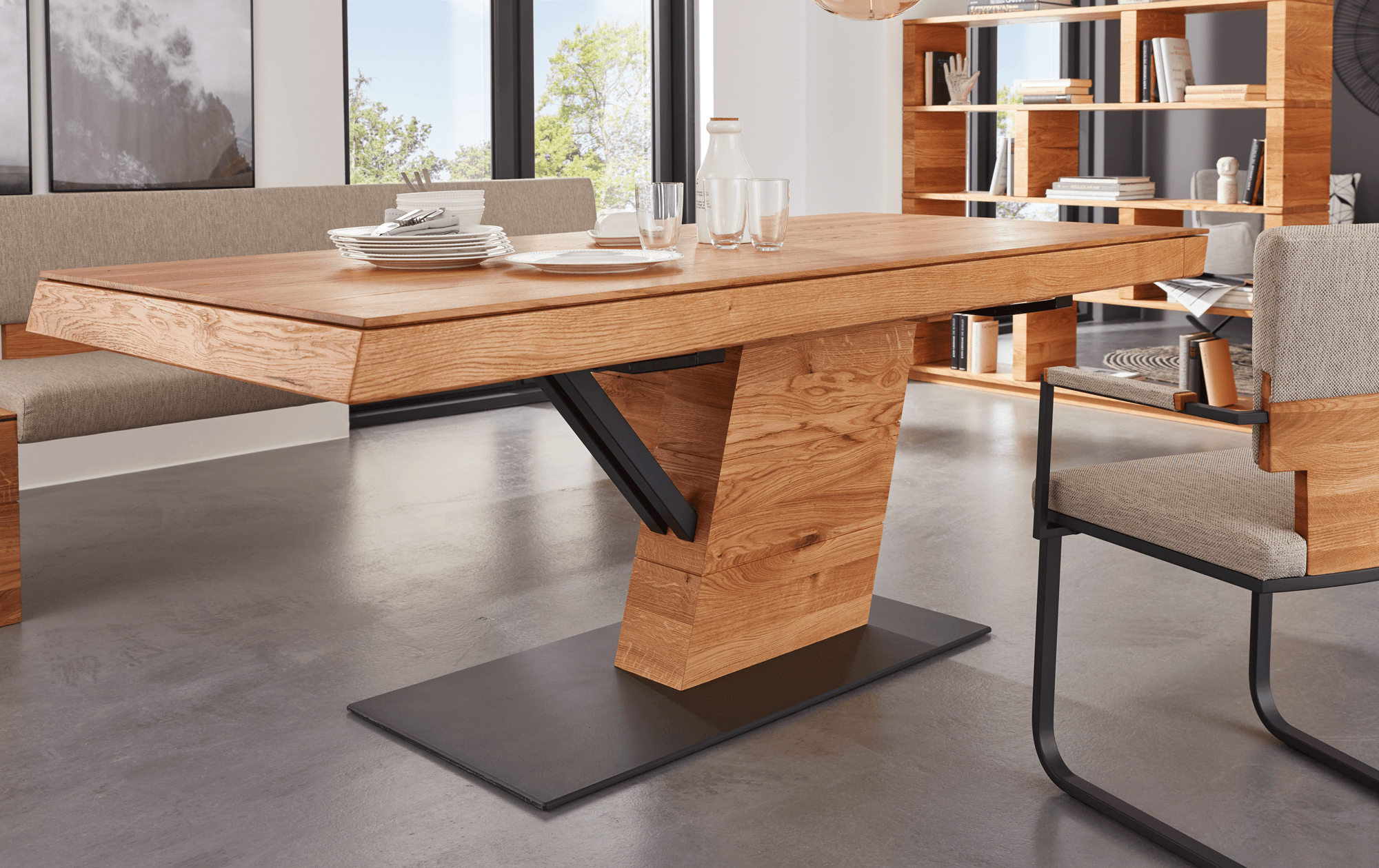 Massiver Esstisch aus Holz mit auffälligem, modernem Mittelfußdesign und schwarzem Metallakzent; arrangiert in einem eleganten Esszimmer mit passenden Möbeln und dekorativen Details.