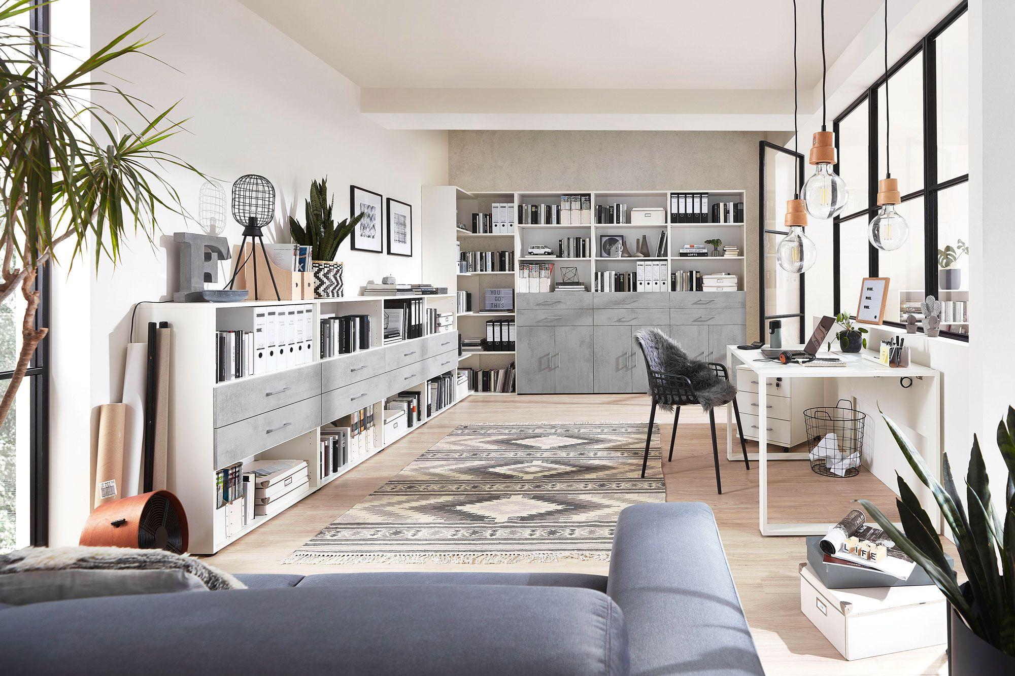 Helles Homeoffice mit Regalsystemen in Betonoptik, Schreibtisch und natürlichen Dekorationen. Eine offene und strukturierte Umgebung für produktives Arbeiten.