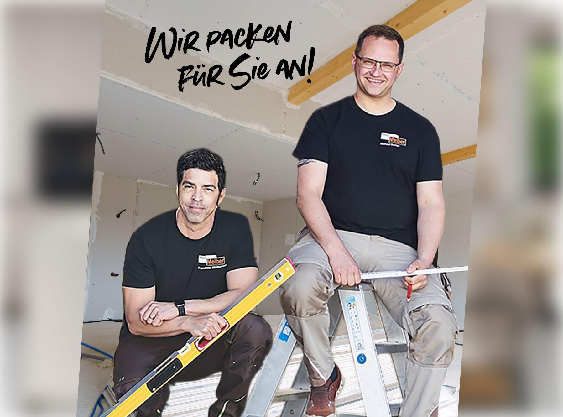 Zwei Melber-Mitarbeiter in schwarzen Firmen-T-Shirts auf einer Baustelle mit Wasserwaage und Zollstock. Schriftzug: „Wir packen für Sie an!"