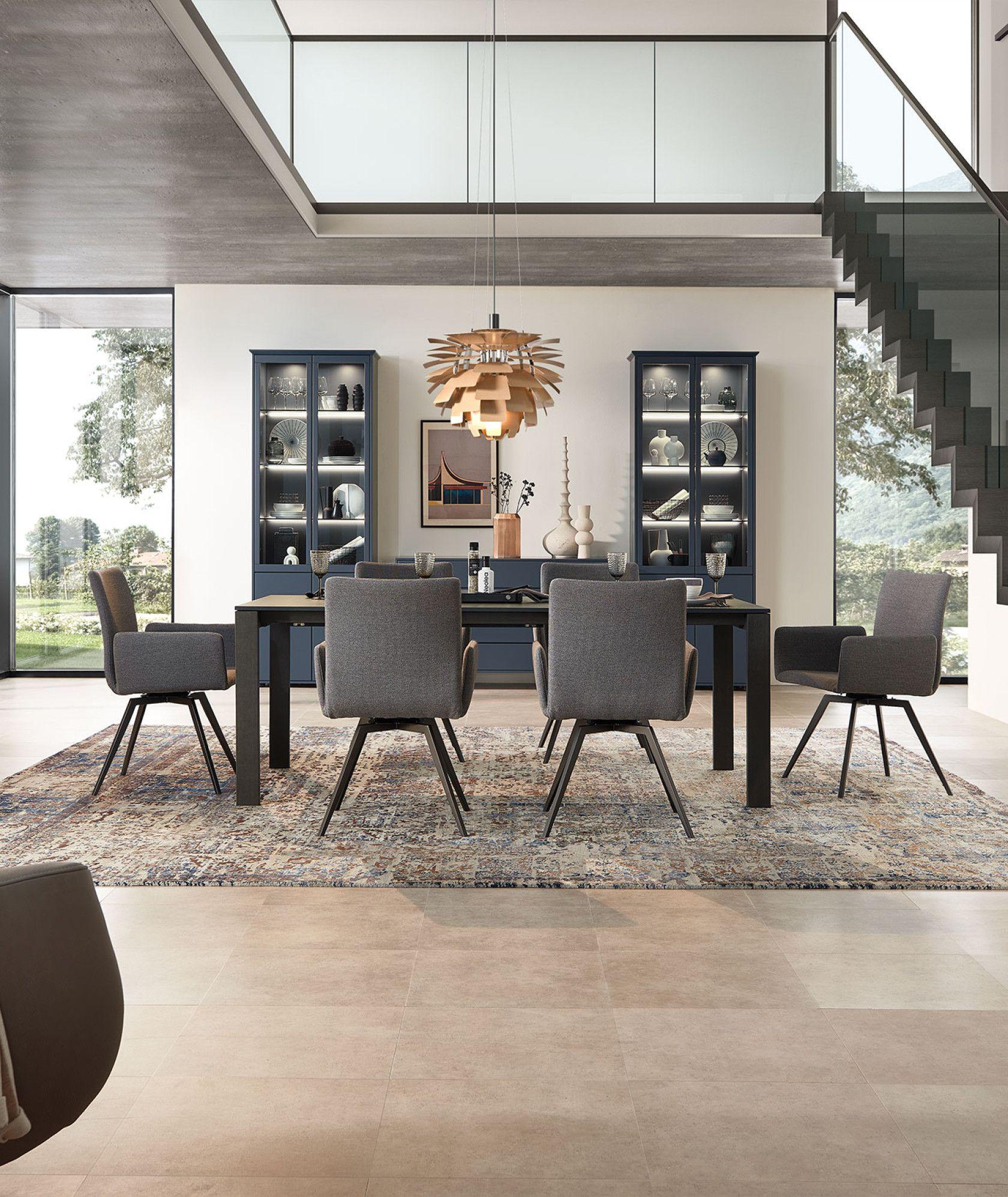 Esszimmer mit grauen Stühlen, einem modernen Tisch und einer markanten Holz-Pendelleuchte.