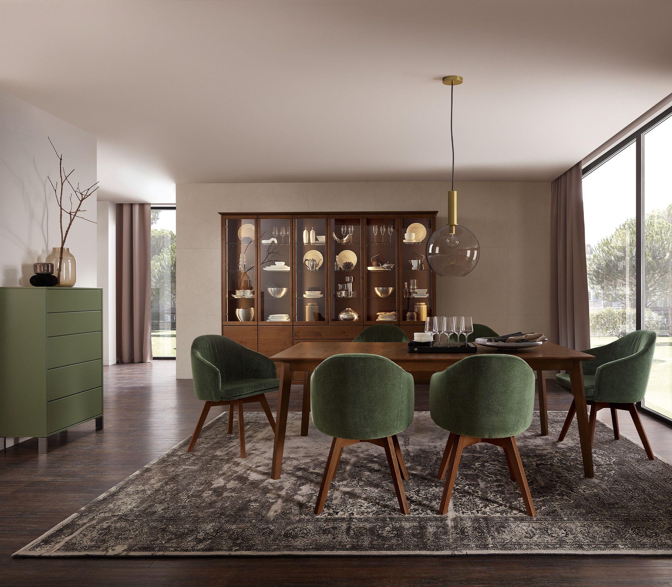 Edles Esszimmer mit grünen Polsterstühlen und einer eleganten Vitrine aus Holz.