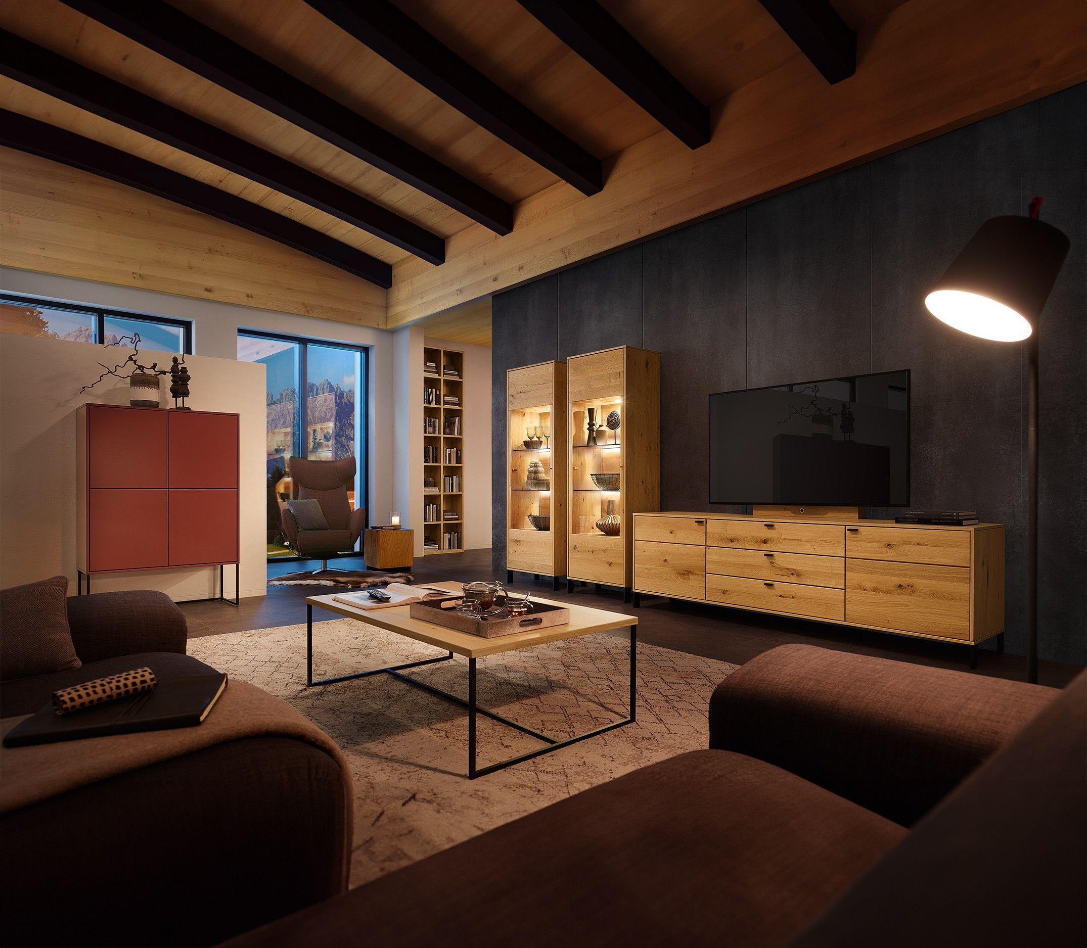 Ein stilvolles Wohnzimmer mit einer Kombination aus modernen und rustikalen Elementen. Ein rotes Sideboard steht neben einem gemütlichen Sessel, während ein niedriger Holztisch in der Mitte des Raumes platziert ist.